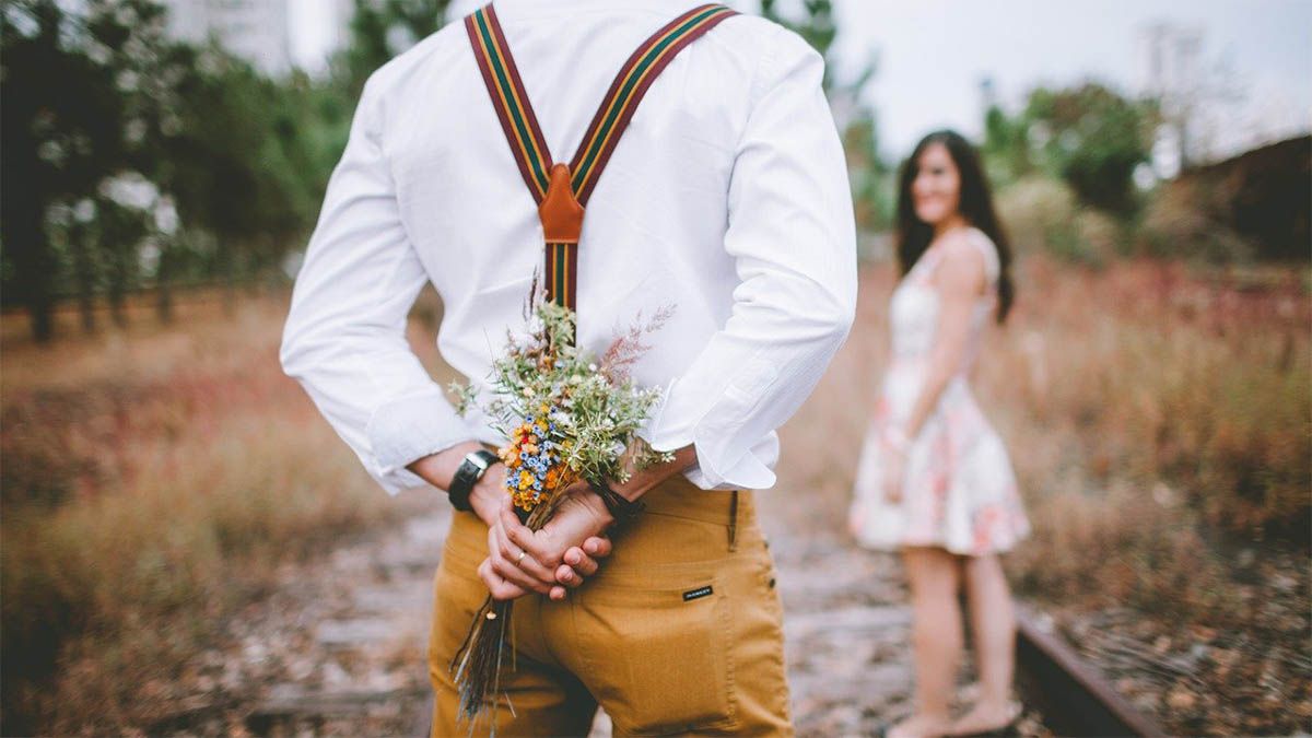mann-mit-blumen-hinter-dem-ruecken