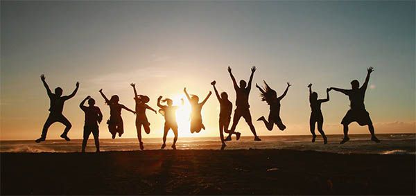 menschen springen am strand sonnenuntergang