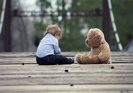 kind mit teddybaer auf terasse