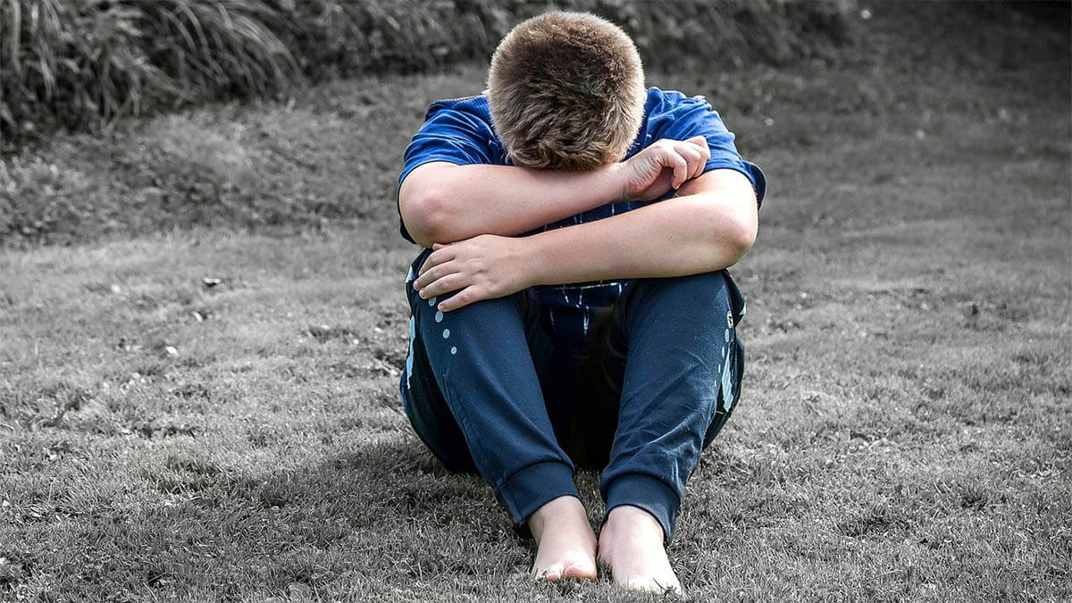 kind-sitzt-traurig-auf-dem-boden-haende-in-gesicht