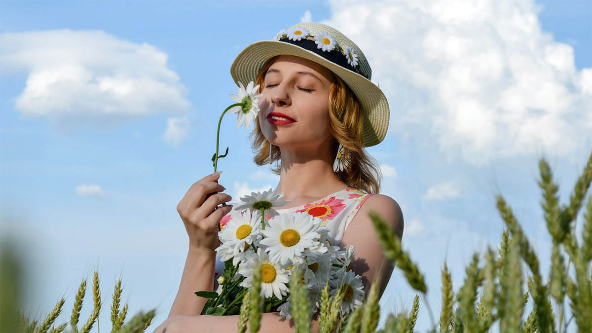 frau-mit-hut-riecht-an-blume