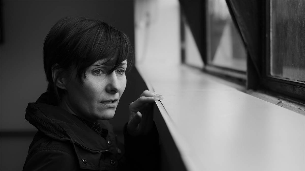frau-traurig-schaut-aus-fenster-schwarz-weiss