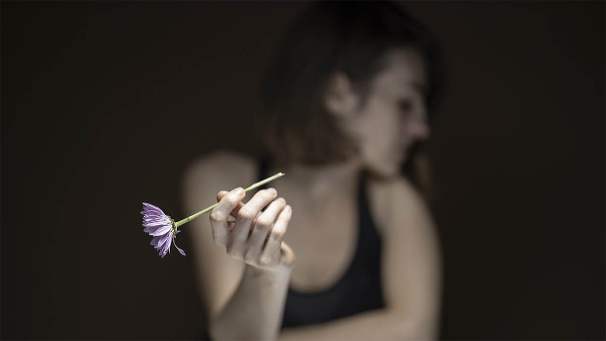 frau-mit-blume-wendet-sich-ab