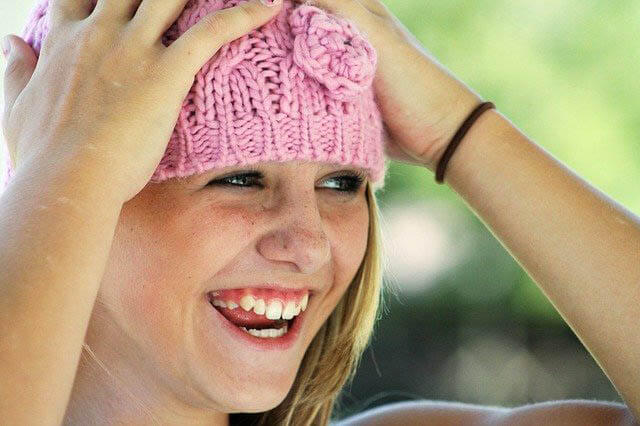 maedchen mit strickmuetze lacht klein