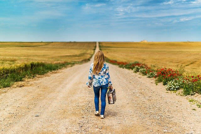 frau mit koffer feldweg