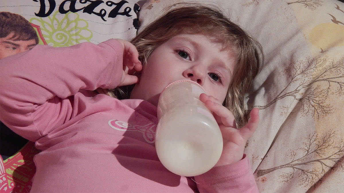 kleinkind im bett mit flaeschchen