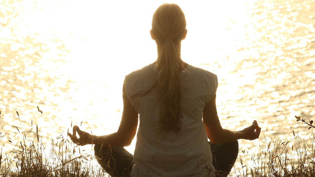 frau-meditiert-am-see-mit-sonne