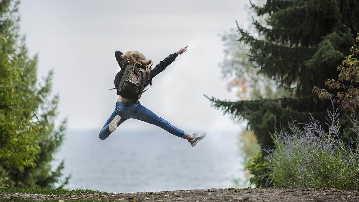 frau mit rucksack springt in die luft