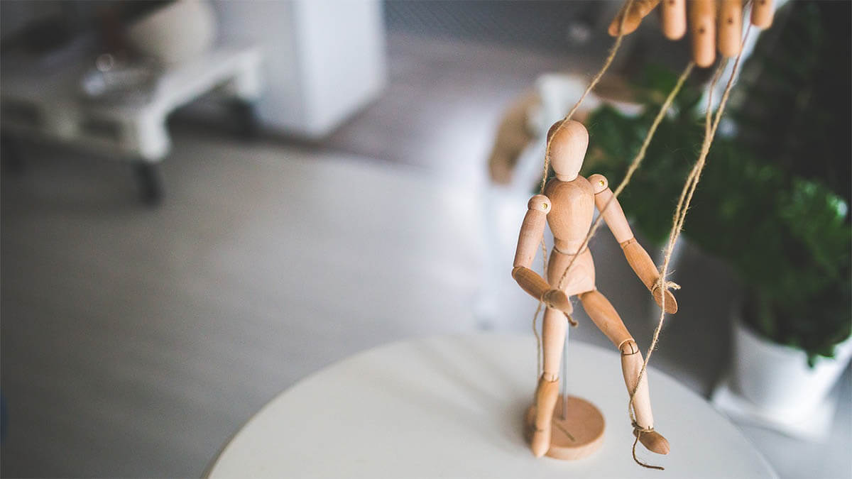 Was ist der Unterschied zwischen Manipulation und Beeinflussung? marionette-an-faeden-tisch